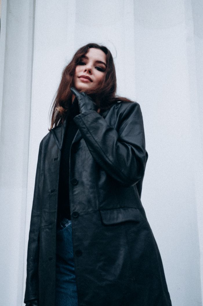 Portrait of a fashionable woman wearing a black leather coat against a white background.