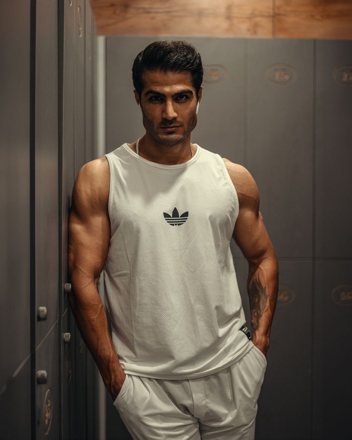 about-02 Muscular man in sportswear standing confidently in a gym locker room, showcasing fitness and strength.