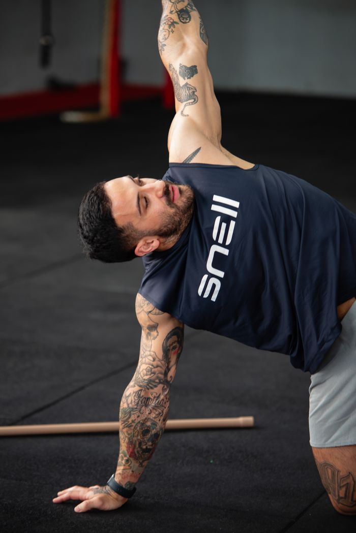 services-img A muscular, tattooed man stretching in a gym showcasing athletic strength.